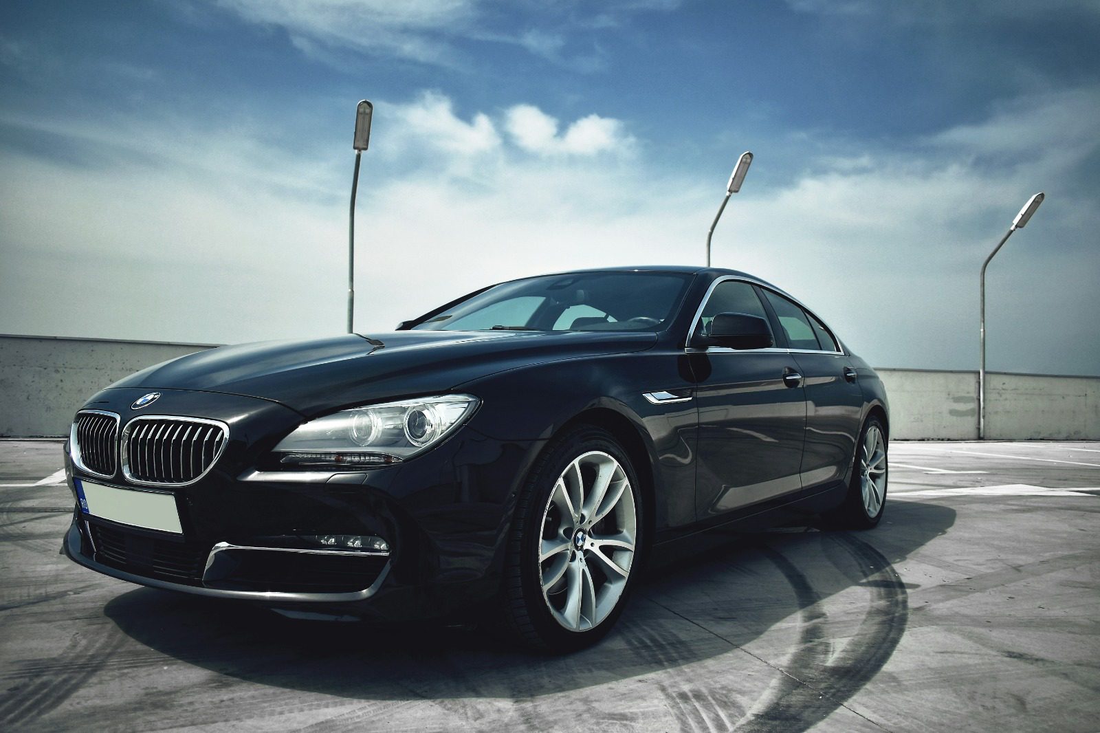 Black BMW Gran Coupe on an open rooftop against a high sky